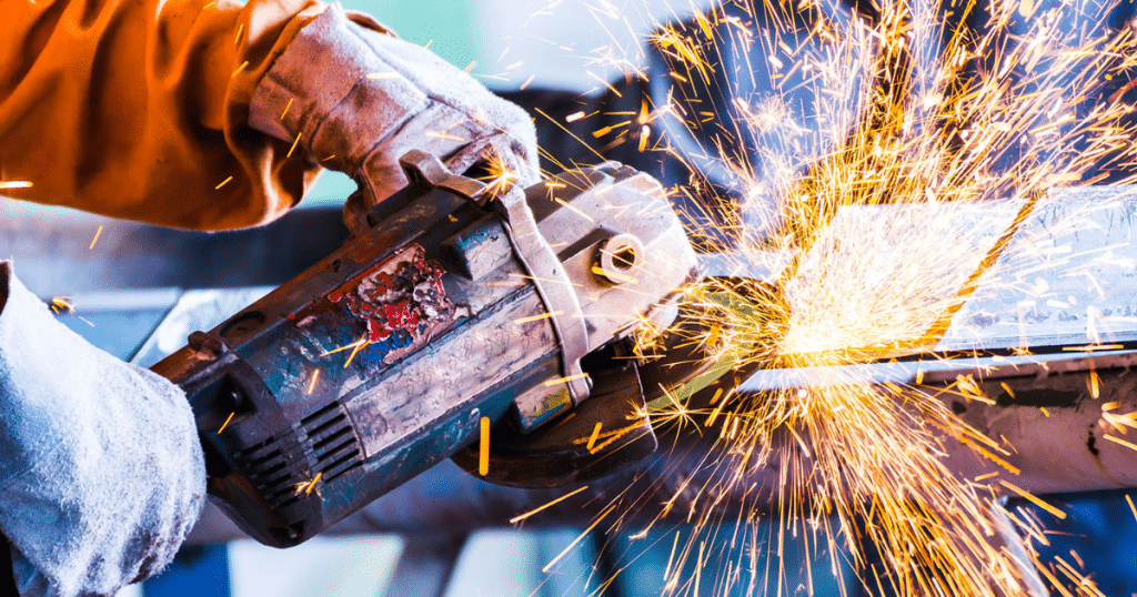 Worker cuts metal, sparks fly.