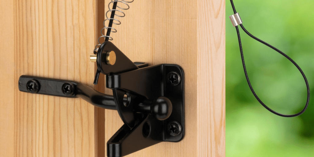 Black gate latch installed on wooden post.