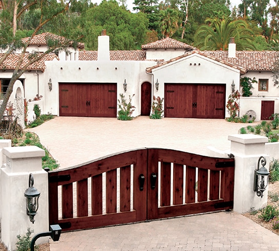 Home with custom entry driveway gate and custom garage doors